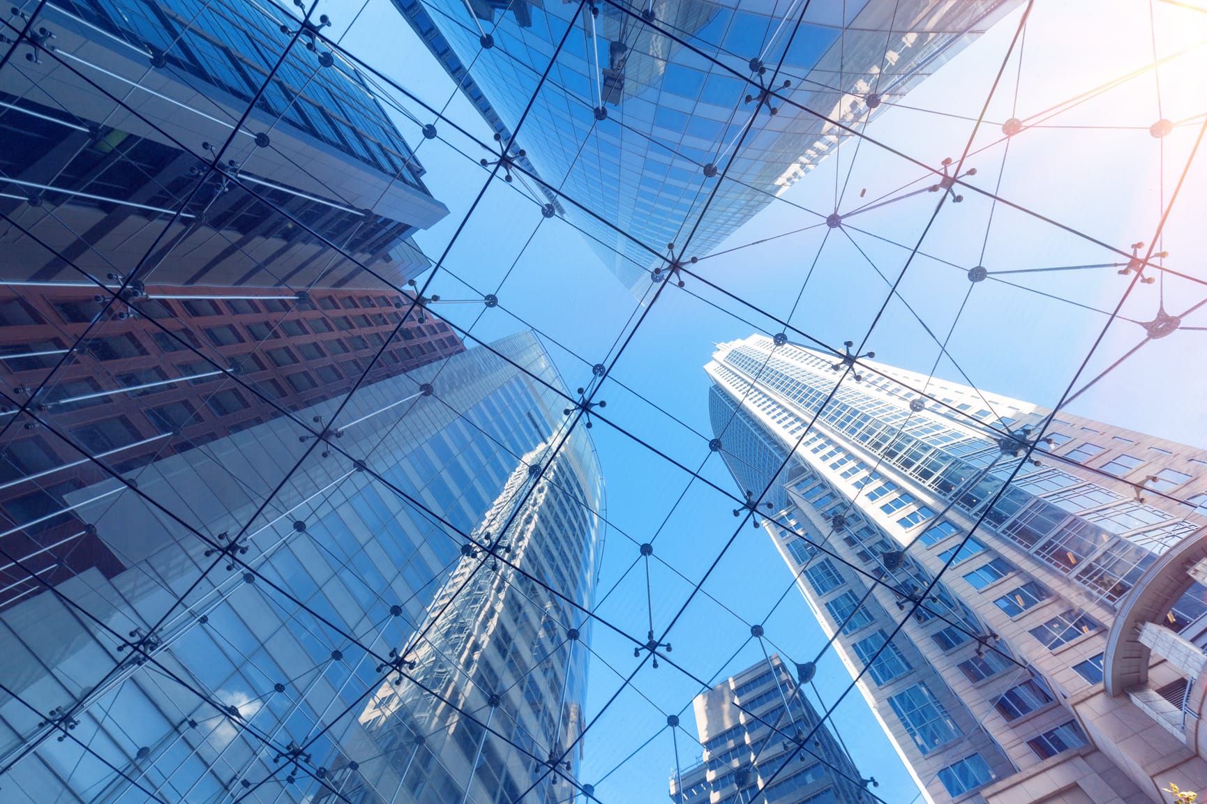 Looking up at the tops off sky scrapers through a glass and wire ceiling