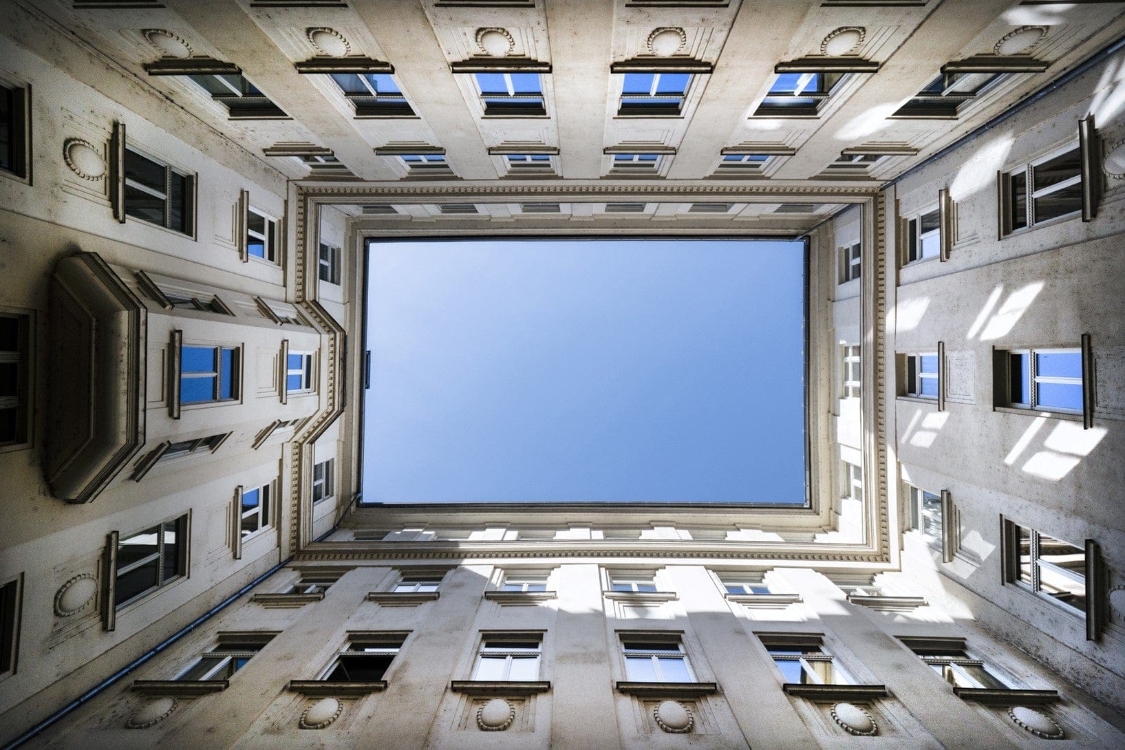 Looking up at the sky from the centre of a four sided building