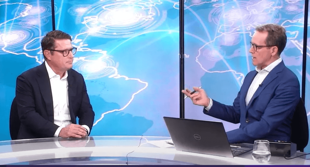 Two men in discussion at rounded table against an abstract glowing background