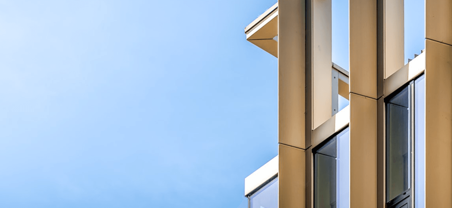 Close up architectural detail of a metal and glass building against a blue sky