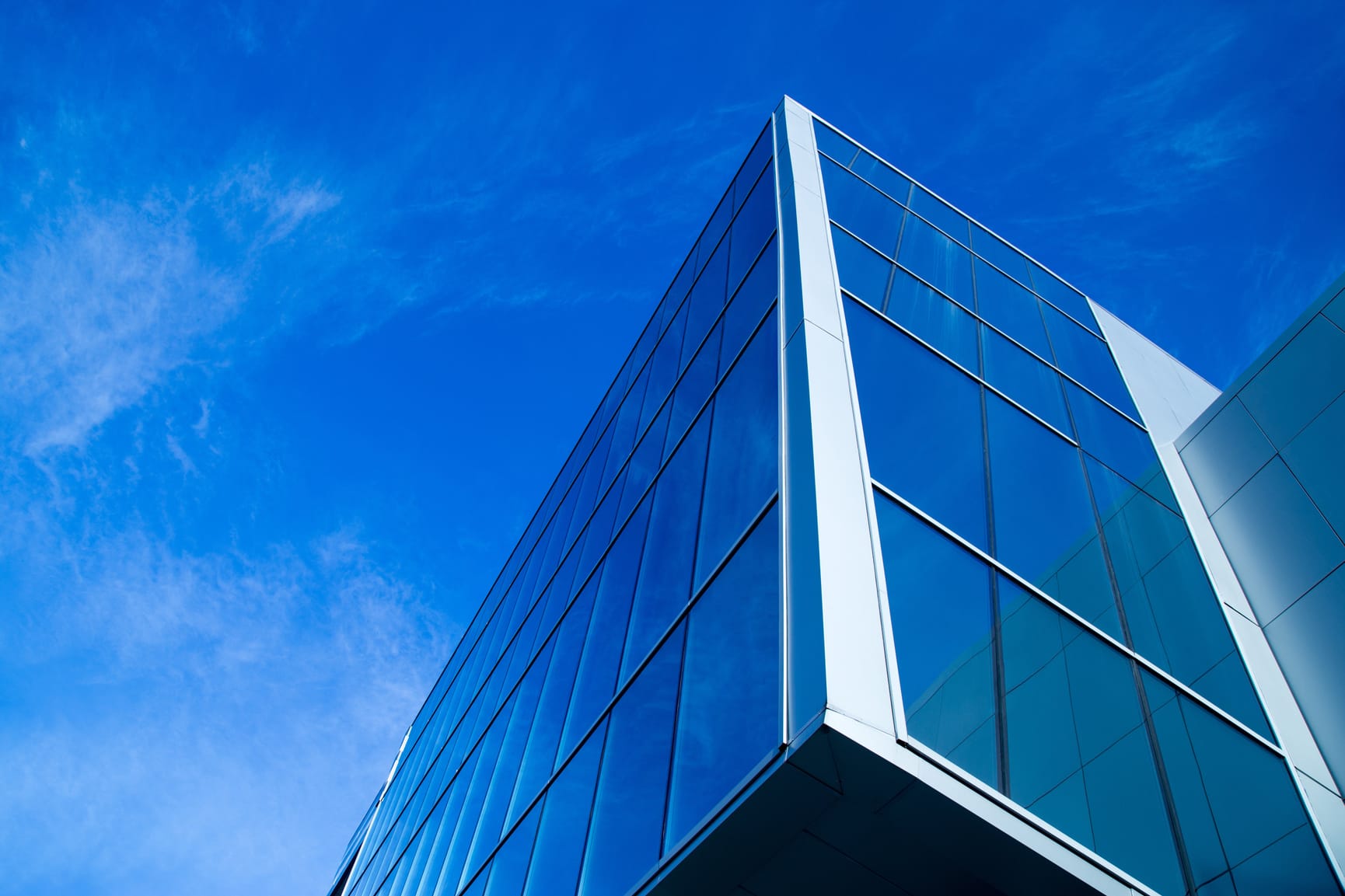 Perspective looking up at a building with the blue sky reflecting on the glass